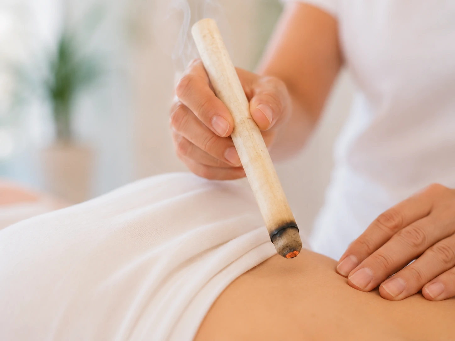 Glimmender Moxa-Kegel über einem Punkt am unteren Rücken einer Patientin im Akupunktur Zentrum Othmarsingen
